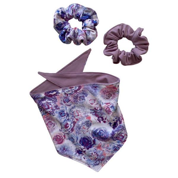 A close-up view of a Reversible Lavender and Pastel Rose Print Dog Swim scARF. The scARF features a soft lavender side on one half and a charming pastel rose print on the other half. Pictured with matching swim scrunchies in the same prints.