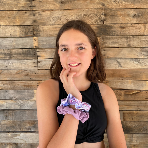 Close up picture of solid lavender swim scrunchie pictured with coordinating pastel rose swim scrunchie, on wrist. Pipevine Designs.