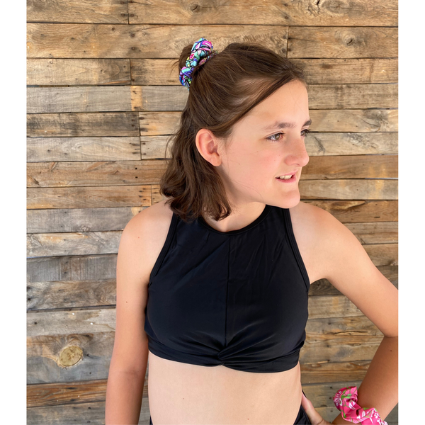 Close up picture of retro flower power swim scrunchie in hair and lime green/hot pink swim scrunchie on wrist. Pipevine Designs.