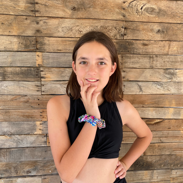 Close up picture of retro flower power swim scrunchie on wrist. Pipevine Designs.