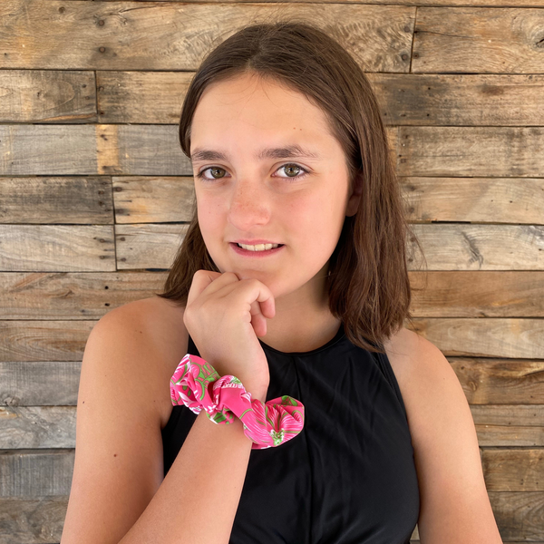 Close up picture of floral print with lime green on hot pink swim scrunchie on wrist. Pipevine Designs.