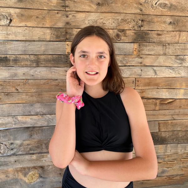 Close up picture of floral print with lime green on hot pink swim scrunchie on wrist. Pipevine Designs.