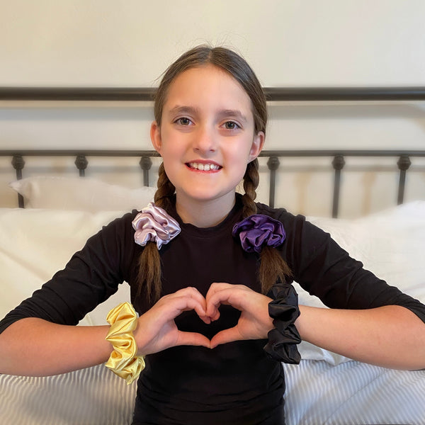 solid black, soft light yellow, light lavender, dark purple satin scrunchies on wrists and in hair