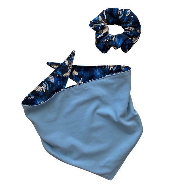 Close up picture of reversible dog swim scARF, aka cooling bandana for dogs. Pictured with a matching swim scrunchie in the same navy blue abstract print. Showcasing a light blue color on one side and an abstract navy blue print on the other side. Pipevine Designs.