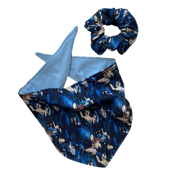 Close up picture of reversible dog swim scARF, aka cooling bandana for dogs. Pictured with a matching navy blue abstract swim scrunchie.. Showcasing a light blue color on one side and an abstract navy blue print on the other side. Pipevine Designs.