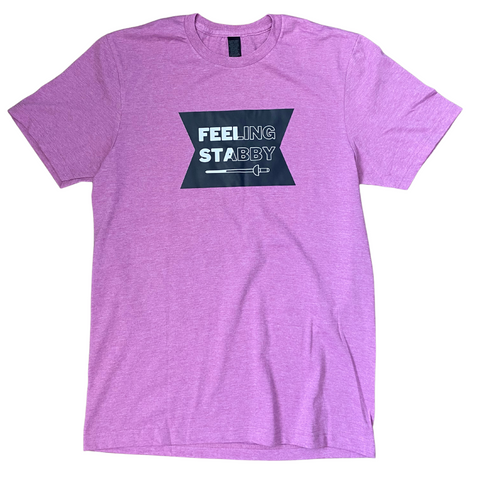 A black emblem, featuring the humorous words, "Feeling Stabby", with a sword below. The words and sword are split diagonally, changing them from having white filling to just an outline, making the whole shirt more eye-catching. A pink adult shirt.