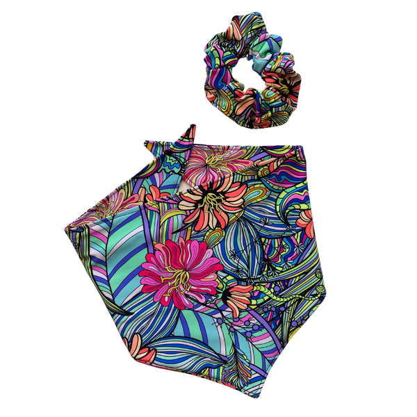 Close up picture, of the retro swim scARF (cooling bandana for dogs). Its bold and colorful floral print will make your pet stand out at the beach or by the pool. Pictured with a matching swim scrunchie. Pipevine Designs