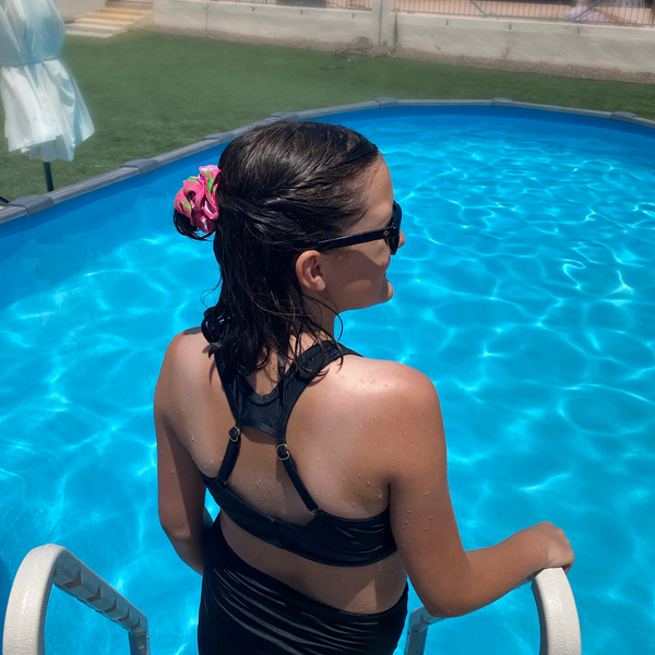 Close up picture of floral print with lime green on hot pink swim scrunchie in wet hair, by a pool. Pipevine Designs.